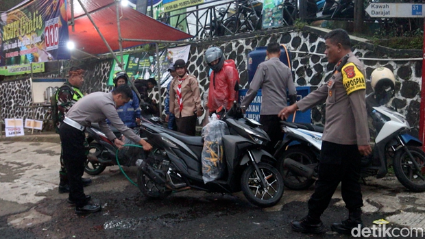 Anggota Polresta Bandung menyiram rem dan mesin motor pemudik agar cepat dingin.