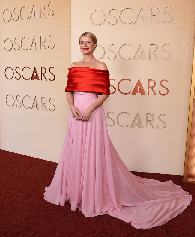 Pemenang Best Actress Jessie Buckley tampil memukau mengenakan gaun Chanel off-shoulder dengan rok merah muda kontras. Busana tersebut terinspirasi dari gaun ikonis yang dikenakan Grace Kelly saat menghadiri Oscars 1956, memberikan sentuhan klasik yang elegan di karpet merah. Foto: REUTERS/DANIEL COLE