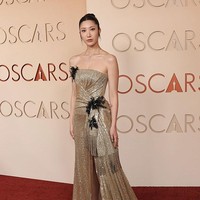 EJAE, pengisi suara Rumi, memakai gaun emas Dior dengan hiasan manik-manik. Bagian tengah gaun memiliki aksen lipatan dan ekor samping dengan ujung berumbai. Foto: Getty Images