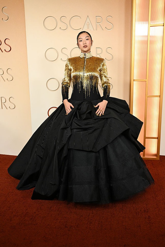 Audrey Nuna memakai siluet avant-garde dengan jaket berkerah tinggi dan ballgown rancangan Thom Browne yang berhias manik-manik emas, mengalir ke rok hitam. Foto: Getty Images