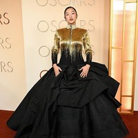 Audrey Nuna memakai siluet avant-garde dengan jaket berkerah tinggi dan ballgown rancangan Thom Browne yang berhias manik-manik emas, mengalir ke rok hitam. Foto: Getty Images
