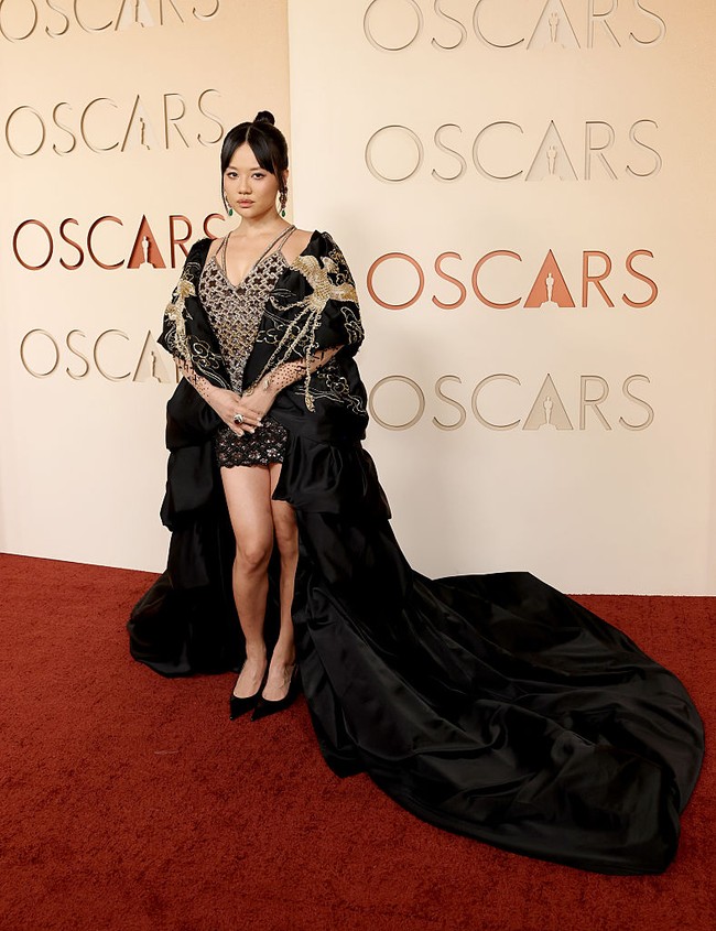 Sementara Rei Ami tampil memukau dengan mini dress berhias manik-manik emas dan hitam. Ia melengkapi penampilannya dengan mantel panjang bergambar burung, yang menyapu lantai. Foto: Getty Images