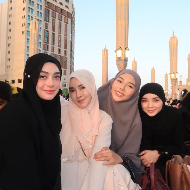 Celine Evangelista tampil anggun dalam balutan hijab hitam saat menjalani ibadah umrah bersama Shandy Purnamasari, Dara Arafah, dan sahabat lainnya menjelang malam terakhir Ramadan 2026. Ketiganya berpose dengan latar belakang kemegahan payung-payung ikonik di pelataran Masjid Nabawi saat senja. Foto: Dok. Instagram @shandypurnamasari.