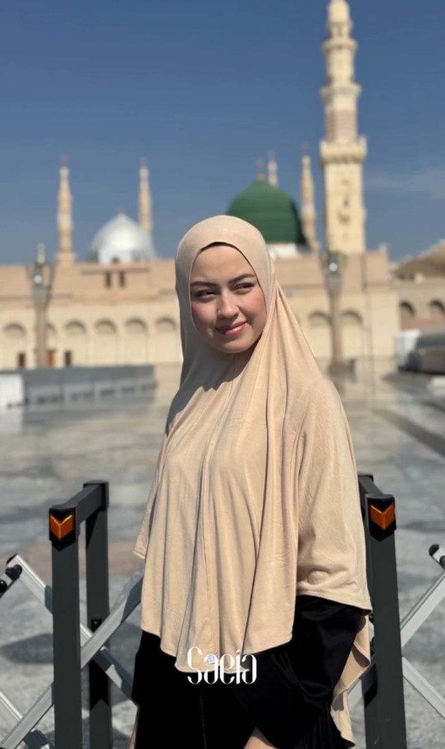 Kimberly Ryder tampil dengan balutan hijab bergo berwarna cokelat muda yang simpel namun elegan saat menjalani ibadah umrah menjelang malam terakhir Ramadan 2026. Kimberly berpose dengan latar belakang kemegahan Masjid Nabawi dan Kubah Hijau yang ikonik di Madinah. Foto: Dok. Instagram @kimbrlyryder.