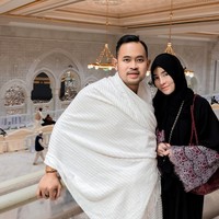 Shandy Purnamasari dan Gilang Widya Pramana tampil serasi dalam suasana penuh kekhusyukan saat menjalani ibadah umrah menjelang malam-malam terakhir Ramadan 2026. Keduanya berpose dengan latar belakang kemegahan arsitektur Masjidil Haram dan pemandangan Kabah yang ikonik. Foto: Dok. Instagram @juragan_99 & @shandypurnamasari.