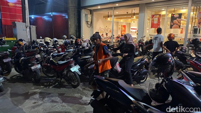 Seorang juru parkir merapikan kendaraan di depan restoran cepat saji di Indramayu, Senin (16/3/2026).