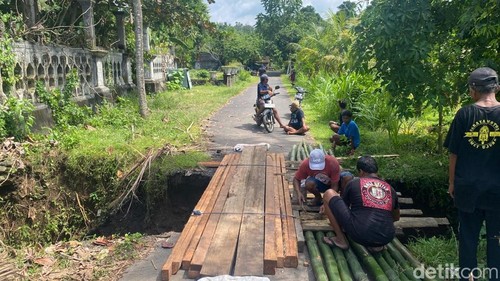Warga membangun jembatan darurat setelah akses jalan terputus di Karangasem, Senin (16/3/2026).