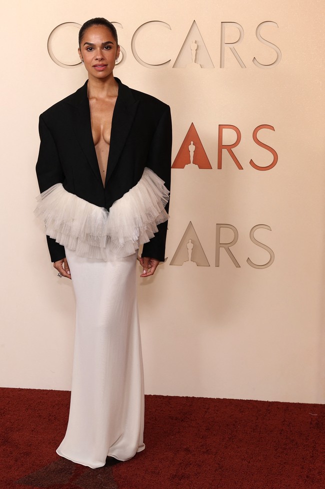 Misty Copeland mengenakan gaun hitam-putih rancangan David Koma yang terinspirasi dari dunia balet. Desainnya memadukan blazer besar dengan detail tulle menyerupai tutu di bagian pinggang. Konsep tersebut dianggap menarik secara ide, tetapi banyak yang menilai tampilan mantan penari utama American Ballet Theatre ini kurang cocok untuk karpet merah Oscars. Meski begitu, Copeland tetap menarik perhatian berkat cincin berlian dari Jared Mpho yang disebut bernilai sekitar USD 1,8 juta. Foto: REUTERS/DANIEL COLE