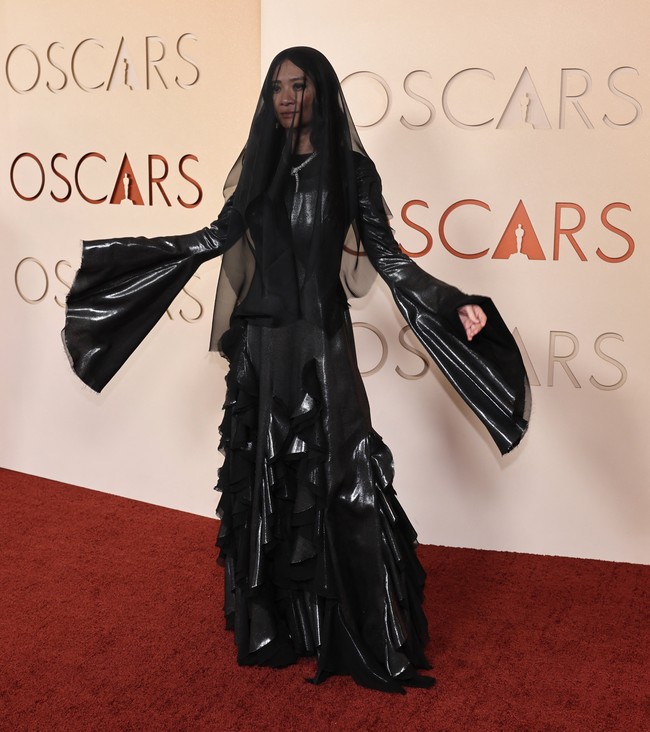 Chloe Zhao tampil dalam gaun hitam rancangan Gabriela Hearst yang memiliki detail ruffle dan lengan lonceng panjang. Penampilan sutradara film ‘Hamnet’ dilengkapi dengan veil hitam yang menutupi kepala. Nuansa serba hitam tersebut membuat sebagian warganet menilai tampilannya terlalu kelam untuk karpet merah. Bahkan ada yang menyamakan gayanya dengan suasana pemakaman.  Foto: REUTERS/DANIEL COLE