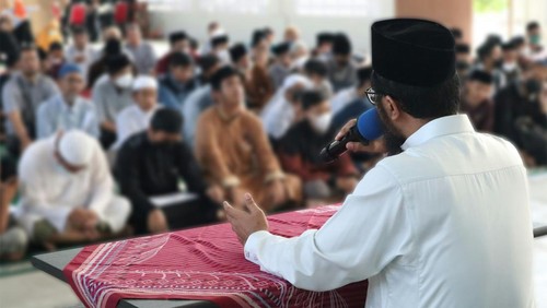 Khatib membawakan khutbah di atas mimbar atau meja kecil.