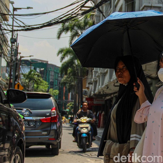 Jakarta Memanas, Warga Berlindung dari Terik dengan Payung