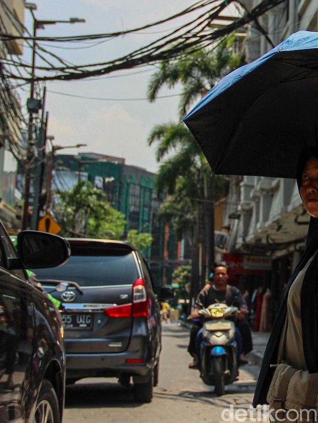 Jakarta Memanas, Warga Berlindung dari Terik dengan Payung