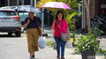 Jakarta Memanas, Warga Berlindung dari Terik dengan Payung
