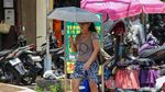 Jakarta Memanas, Warga Berlindung dari Terik dengan Payung