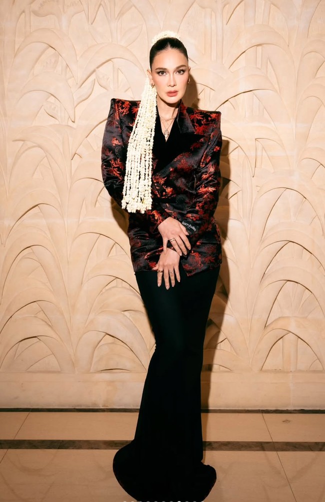 Luna mengenakan blazer berpotongan tegas dengan motif merah menyala di atas dasar hitam. Busana ini merupakan rancangan desainer Indonesia Harry Halim. Motif merah yang menyerupai corak floral atau abstrak memberi kesan bold sekaligus artistik. Foto: Instagram/@lunamaya
