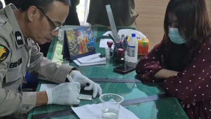 Petugas kepolisian saat melakukan tes urine kepada pengemudi wanita. (dok. Polres Binjai)