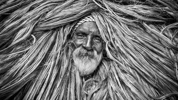 Nama Fotografer: Pinu Rahman, Judul Fotor: Threads of Life. Deskripsi Gambar: Potret seorang buruh goni yang membawa bundel goni mentah dari sungai ke gudang ini menangkap ketahanan dan kesulitan di balik industri goni Bangladesh. Nada serat menyatu dengan jenggot dan wajah subjek, melambangkan berat dan intensitas karyanya.Copyright: © Pinu Rahman, Bangladesh, Winner, National Awards, Sony World Photography Awards 2026