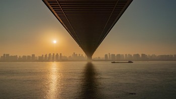 Nama Fotografer: Eng Tong Tan Deskripsi Gambar: Menggunakan bagian bawah jembatan untuk menciptakan titik lenyap yang kuat, foto ini menarik mata pemirsa ke arah cakrawala, di mana struktur, air, dan kota bertemu. Garis yang menyempit menekankan kedalaman dan skala, mengubah jembatan menjadi jalur visual antara lanskap perkotaan dan cahaya yang memudar. Hak Cipta: © Eng Tong Tan, Malaysia, Winner, National Awards, Sony World Photography Awards 2026