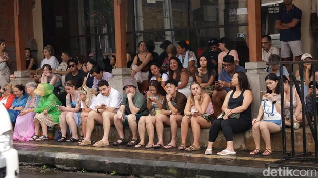 Antusiasme para turis asing menunggu penampilan ogoh-ogoh saat diguyur hujan di catus pata Ubud Jalan Suweta, Ubud, Gianyar, Rabu (18/3/2026). (Aryo Mahendro/detikBali)