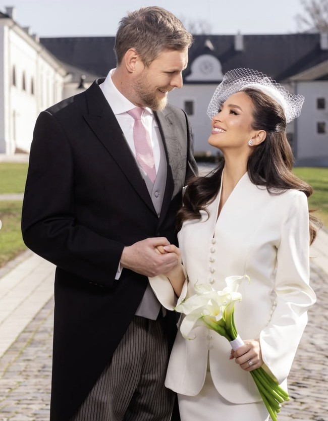 Dalam foto resmi, Leka tampil dengan setelan klasik, sementara Blerta mengenakan setelan rok putih yang elegan, lengkap dengan topi ber-veil model birdcage dan buket kecil bunga calla lily. Keduanya tampak mesra dan bahagia. Foto: dok. Instagram