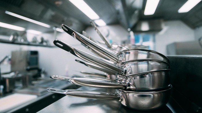Stacks of metal frying pans on a counter in a professional kitchen
Blurred background