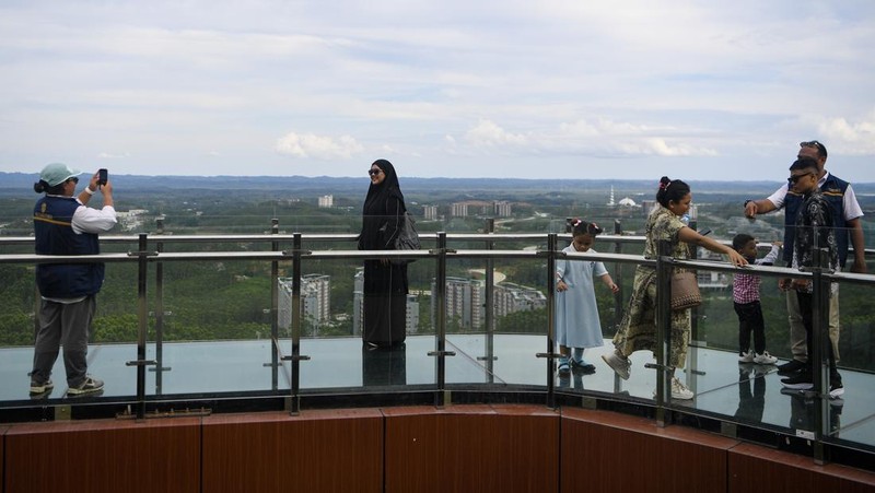 Sejumlah pengunjung berfoto saat berjalan di atas jembatan kaca di glamping Kawasan Inti Pusat Pemerintahan (KIPP) Ibu Kota Nusantara (IKN), Penajam Paser Utara, Kalimantan Timur, Sabtu (21/3/2026). Menurut petugas, jembatan kaca yang dibuka untuk umum saat libur Lebaran 2026 guna menikmati pemandangan kawasan IKN dari ketinggian itu telah dikunjungi sekitar 2.773 orang pengunjung. ANTARA FOTO/M Risyal Hidayat/rwa.
