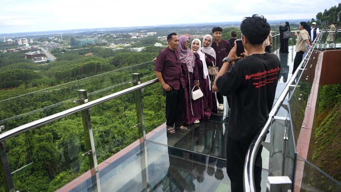 Sejumlah pengunjung berfoto saat berjalan di atas jembatan kaca di glamping Kawasan Inti Pusat Pemerintahan (KIPP) Ibu Kota Nusantara (IKN), Penajam Paser Utara, Kalimantan Timur, Sabtu (21/3/2026). Menurut petugas, jembatan kaca yang dibuka untuk umum saat libur Lebaran 2026 guna menikmati pemandangan kawasan IKN dari ketinggian itu telah dikunjungi sekitar 2.773 orang pengunjung. ANTARA FOTO/M Risyal Hidayat/rwa.