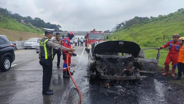 Bangkai mobil Ford EcoSport yang terbakar di Tol Semarang-Solo sedang didinginkan oleh petugas pada Sabtu (21/3/2026).