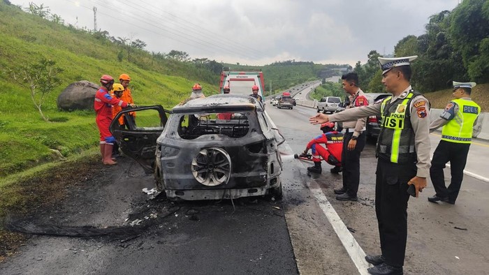 Bangkai mobil Ford EcoSport yang terbakar di Tol Semarang-Solo sedang didinginkan oleh petugas pada Sabtu (21/3/2026).