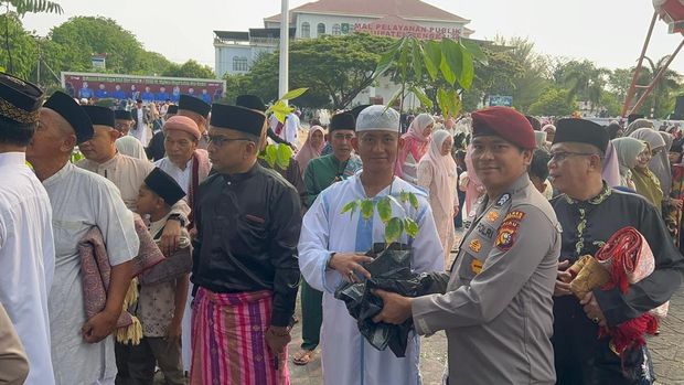 Personel Polres Bengkalis memberikan bibit pohon kepada masyarakat seusai Salat Id di Mapolres Bengkalis, Riau, pada Sabtu (21/3/2026).