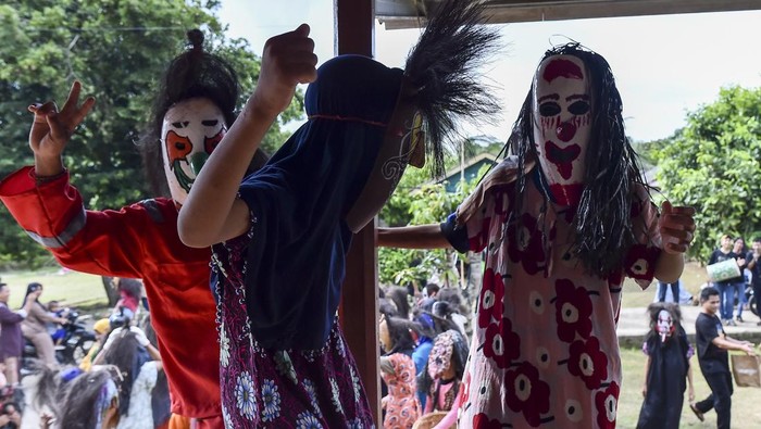 Warga menyambut anggota Perkumpulan Rumah Menapo yang menari sambil mengenakan topeng labu dan pakaian unik saat melaksanakan tradisi Topeng Labu di Desa Muara Jambi, Muaro Jambi, Jambi, Sabtu (21/3/2026). Atraksi Topeng Labu yang berangkat dari cerita rakyat tentang siasat para penderita kusta untuk menemui keluarga saat mereka diasingkan ke hutan pada masa lampau tersebut merupakan tradisi turun temurun masyarakat Desa Muara Jambi pada hari pertama Idul Fitri. ANTARA FOTO/Wahdi Septiawan/rwa.