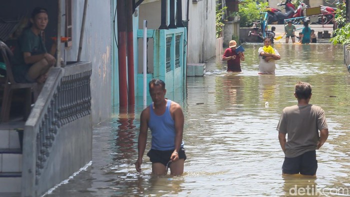 Warga beraktivitas saat banjir merendam kawasan Kampung Dukuh, Ciracas, Jakarta, Minggu (22/3/2026). Hujan deras yang mengguyur Jakarta sejak Sabtu sore menyebabkan sejumlah titik permukiman terendam banjir.