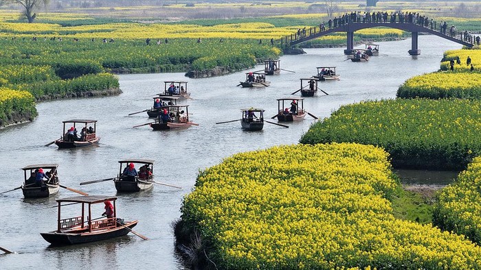 XINGHUA, CHINA - MARCH 21: Aerial view of tourists enjoying rapeseed flowers by boat at the Qianduo scenic area in spring on March 21, 2026 in Xinghua, Jiangsu Province of China. (Photo by Meng Delong/VCG via Getty Images)