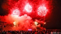 Pengunjung antusias menikmati pertunjukan kembang api di tepi pantai.