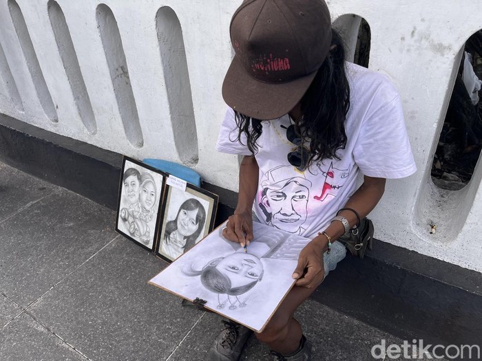 Setiawan, pelukis karikatur di kawasan Malioboro, Kota Jogja, Minggu (22/3/2026),