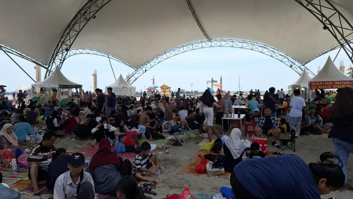 Pengunjung menikmati piknik di Ancol dengan membawa menu khas Lebaran, seprerti opor dan rendang.