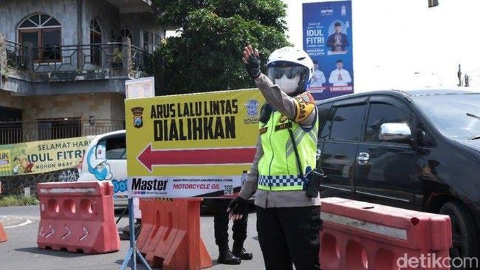 Petugas mengarahkan kendaraan untuk mengikuti pengalihan arus yang dilakukan.