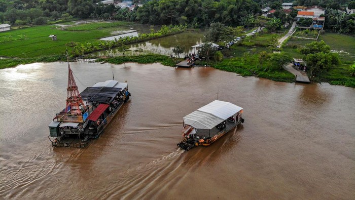 Foto udara perahu penyeberangan melintas di Sungai Brantas di Jatikalen, Nganjuk, Jawa Timur, Minggu (22/3/2026). Pada hari kedua Idul Fitri 1447 Hijriah, perahu penyeberangan yang menghubungkan Kabupaten Nganjuk dengan Kabupaten Jombang itu jumlah pengguna jasanya meningkat dibanding hari biasanya yakni dari sekitar lima ratus kendaraan per hari menjadi seribu kendaraan per hari dengan tarif Rp2 ribu untuk roda dua, Rp5 ribu untuk roda empat, dan untuk penumpang pejalan kaki gratis. ANTARA FOTO/Muhammad Mada/wsj.