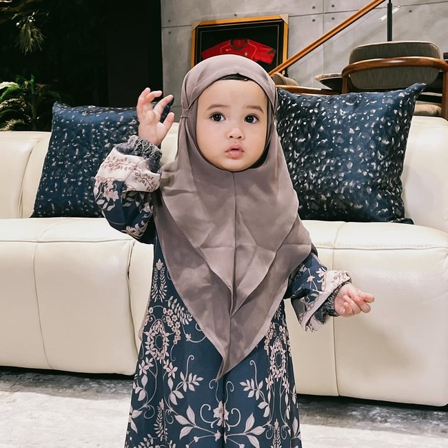 Azura Humaira Nur Atta, putri kedua pasangan Atta Halilintar dan Aurelie Hermansyah, tampil menggemaskan dalam balutan hijab instan berwarna cokelat yang menonjolkan pipi chubby-nya. Dengan tatapan matanya yang bulat dan ekspresi polos saat berpose mengenakan gamis bermotif floral, Azura sukses membuat para penggemar keluarga AH merasa gemas dan terpesona. Foto: Dok. Instagram @attahalilintar, @azuraatta, @ameenaatta, & @aurelie.hermansyah.