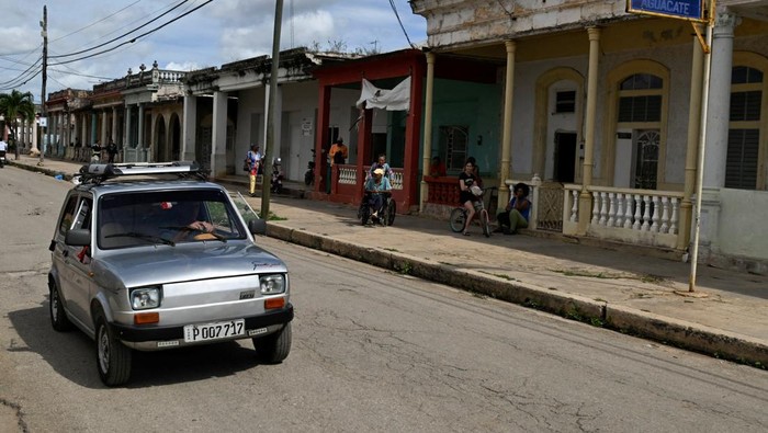 Cuban mechanic Juan Carlos Pino, 56 and his nephew put charcoal into a welded fuel tank to fuel Pino's modified 1980 Polish‑built Polski car, adapted to run on charcoal, a cheaper and more abundant alternative to gasoline since the United States cut off oil shipments to the Caribbean island, in Aguacate, Cuba, March 16, 2026. REUTERS/Norlys Perez