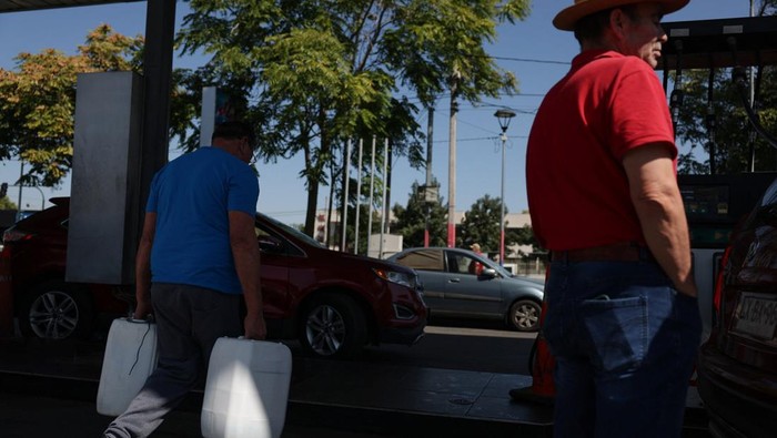 A man waits for his car to finish filling up with fuel at a gas station as fuel prices in the country are expected to rise, amid the U.S.-Israeli conflict with Iran, in Santiago, Chile, March 24, 2026. REUTERS/Pablo Sanhueza