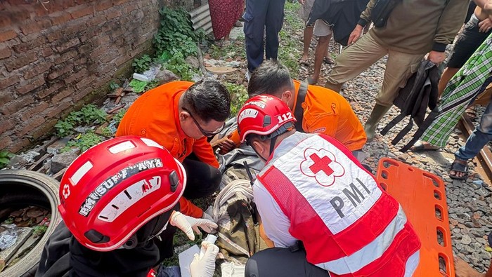 Petugas mengevakuasi korban setelah tertabrak KA di Jalan Dupak Timur 4 Kecamatan Bubutan, Surabaya