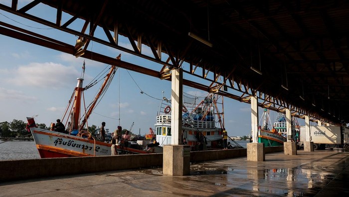 Fishermen transfer a container of catch from a trawler to a truck at a pier, as rising diesel prices have left many trawlers docked due to unprofitable operations, in Samut Sakhon province, Thailand, March 25, 2026, REUTERS/Chalinee Thirasupa