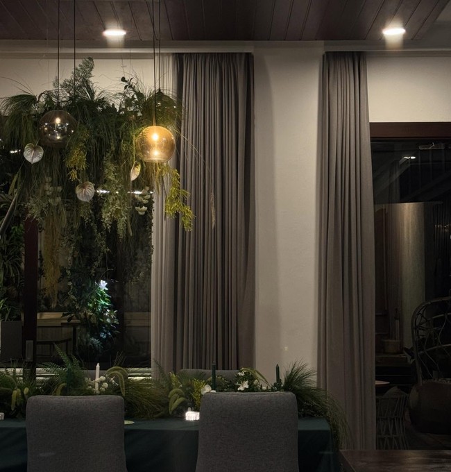 Lampu pencahayaan berwarna kuning menambah kesan hangat pada ruangan. Perpaduan warna coklat pada dinding, kusen, serta tirai jendela menambah suasana alam di dalam rumah Rachel. Foto: Instagram/@ber_bungabungi/@rachelvennya