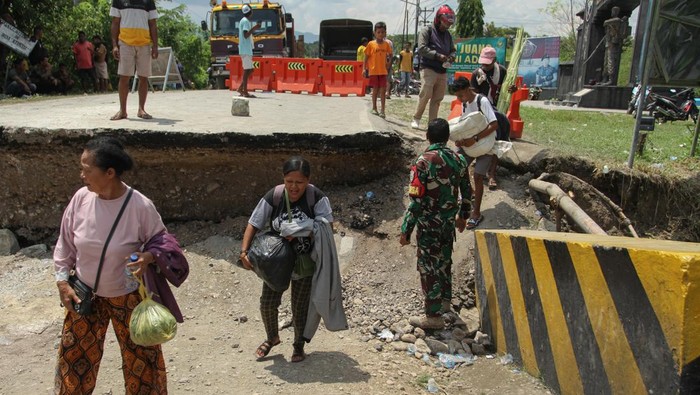 Sejumlah warga melintasi jembatan Oelmasi yang amblas di jalan Trans Pulau Timor, Kecamatan Kupang Timur, Kabupaten Kupang, Nusa Tenggara Timur, Kamis (26/3/2026). Jembatan tersebut amblas pada sisi timur menuju ke Atambua pada Rabu (25/3) sehingga memutus jalur kendaraan dari Kupang ke Atambua hingga Timor Leste dan sebaliknya. ANTARA FOTO/Mega Tokan/bar