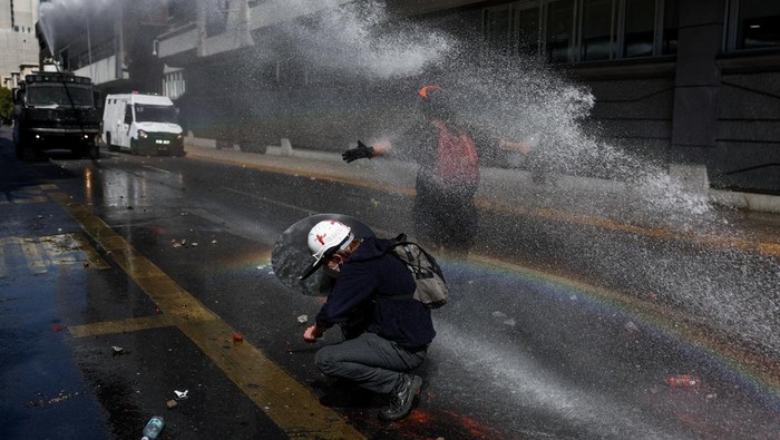 A demonstrator throws an object as a water cannon is used during a protest against the Chilean government's budget cuts to education, in Santiago, Chile, March 26, 2026. REUTERS/Pablo Sanhueza