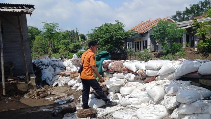 Tanggul yang jebol imbas banjir luapan Sungai Petung di Kota Pasuruan ditambal pakai karung berisi pasir.