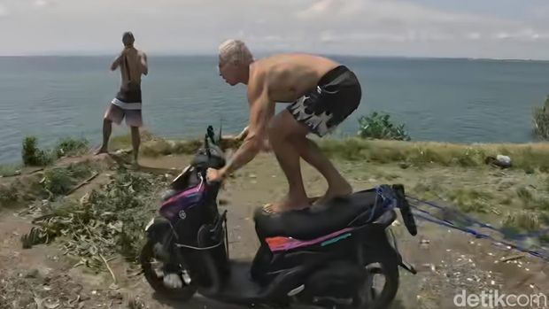 Bule melakukan aksi lompat dari tebing ke laut menggunakan sepeda motor di Pantai Balangan, Kuta Selatan, Badung, Bali. Bule melakukan aksi lompat dari tebing ke laut menggunakan sepeda motor di Pantai Balangan, Kuta Selatan, Badung, Bali.