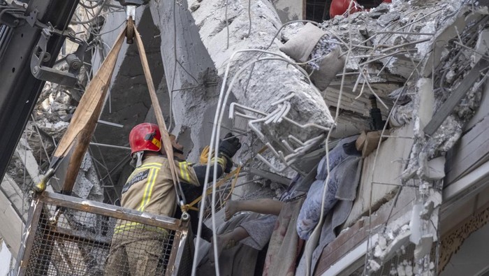 Iranian firefighters work to recover the body of an Afghan woman from the ruins of a residential building in Tehran, Iran, on March 27, 2026. The building was struck during a military operation involving the United States and Israel. (Photo by Morteza Nikoubazl/NurPhoto via Getty Images)