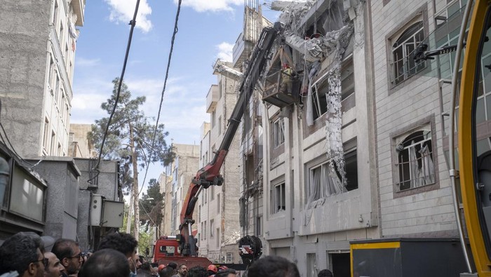 Iranian firefighters work to recover the body of an Afghan woman from the ruins of a residential building in Tehran, Iran, on March 27, 2026. The building was struck during a military operation involving the United States and Israel. (Photo by Mortez